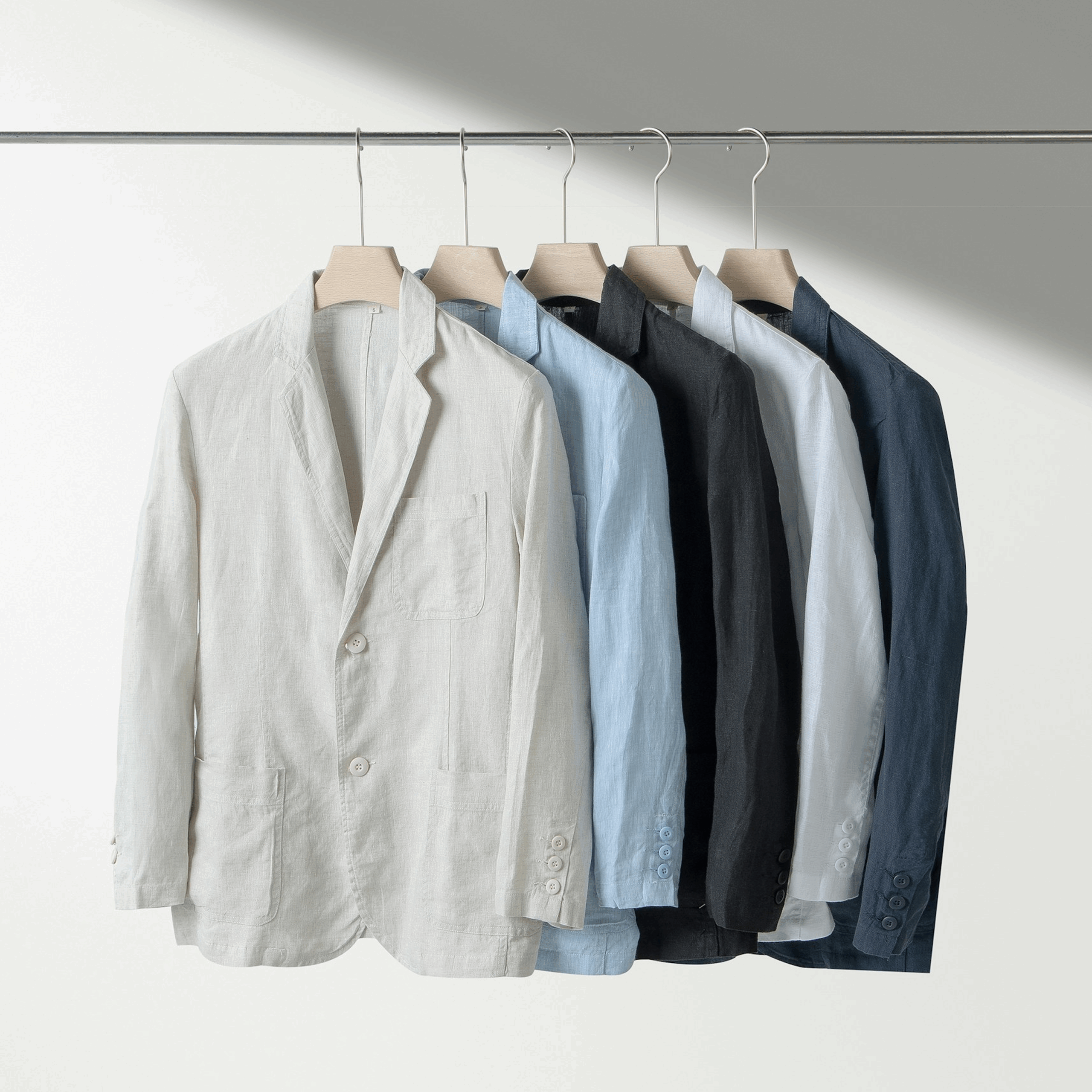 Assorted linen blazers in multiple colours hanging on a clothing rack.